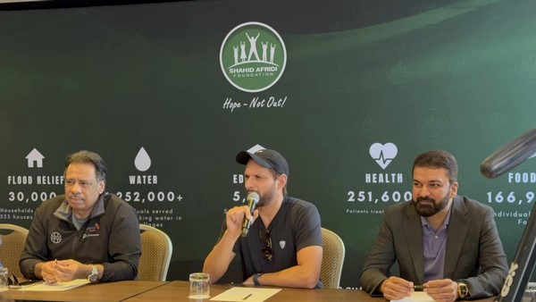 A group of men sitting at a table talking into a microphone
Description automatically generated