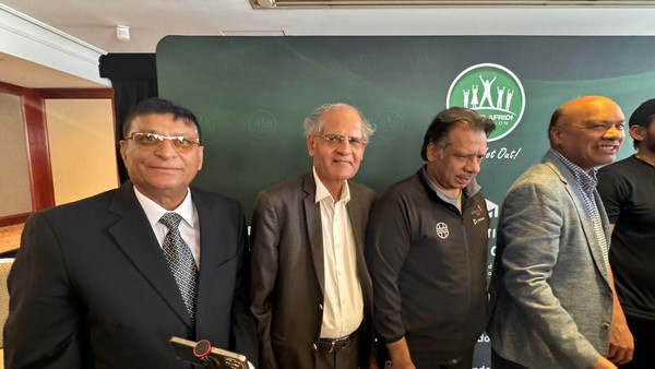 A group of men standing in front of a green board
Description automatically generated