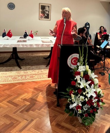 A person in a red dress standing at a podium with a microphone

Description automatically generated