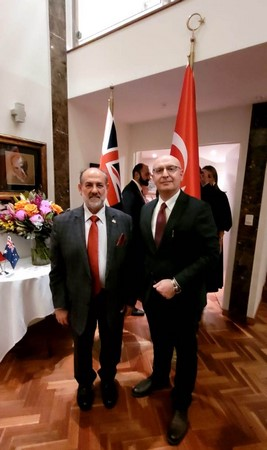 Two men standing in a room with flags

Description automatically generated