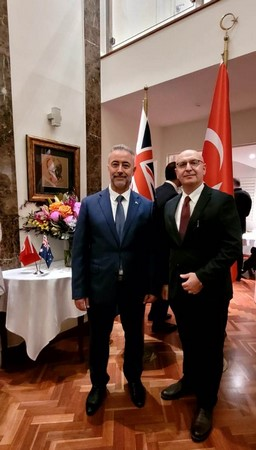 Two men standing in a room with flags

Description automatically generated