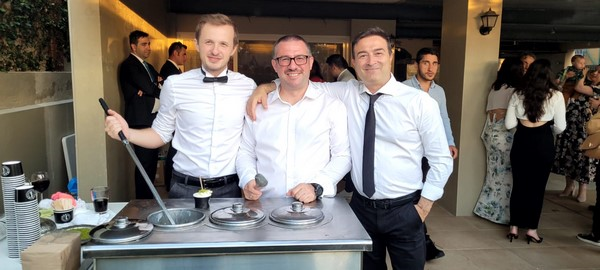 A group of men standing next to a table

Description automatically generated