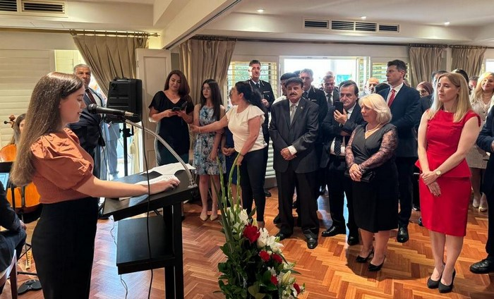 A person standing at a podium with a crowd of people around it

Description automatically generated