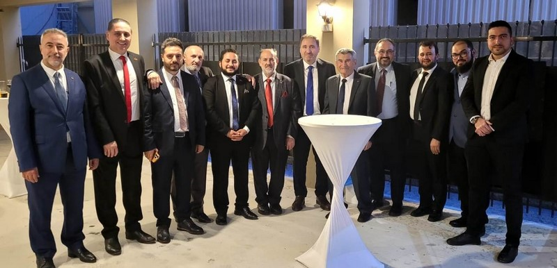 A group of people standing in front of a white table

Description automatically generated
