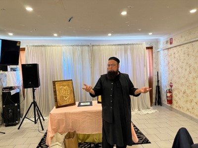 A person in a black robe standing in front of a table with a picture

Description automatically generated