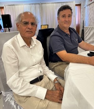 A couple of men sitting at a table

Description automatically generated