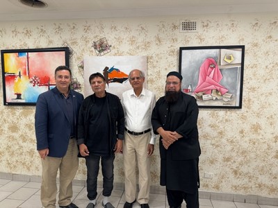 A group of men standing in front of paintings

Description automatically generated