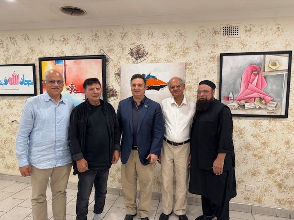A group of men standing in front of paintings

Description automatically generated