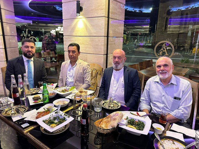 A group of men sitting at a table with food

Description automatically generated