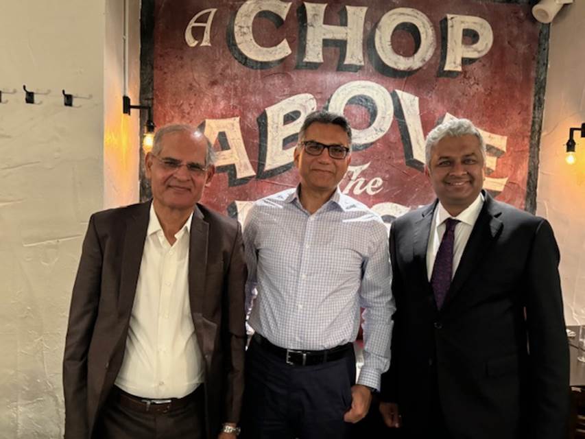 A group of men standing in front of a sign
Description automatically generated