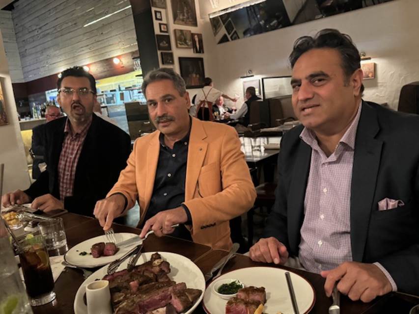 A group of men sitting at a table with plates of food
Description automatically generated