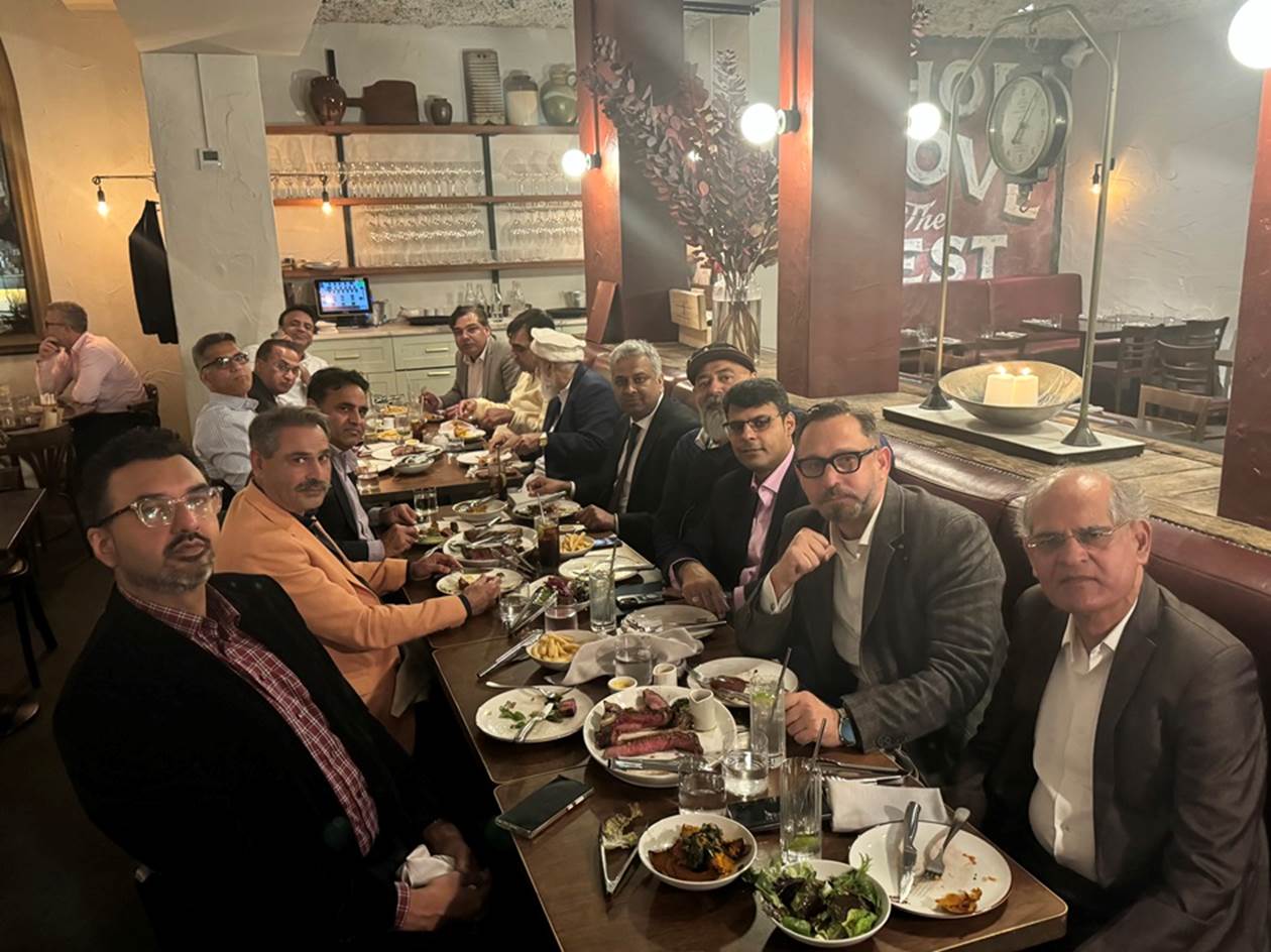 A group of people sitting at a long table with food
Description automatically generated