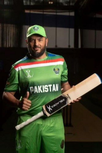 A person in a green uniform holding a bat
Description automatically generated