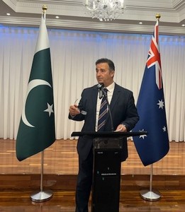 A person standing at a podium with flags behind him
Description automatically generated