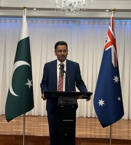 A person standing at a podium with flags behind him
Description automatically generated