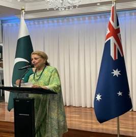 A person standing at a podium with flags behind her
Description automatically generated
