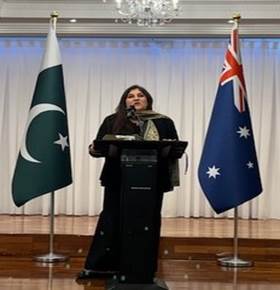 A person standing at a podium with flags behind her
Description automatically generated