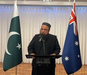 A person standing at a podium with a microphone and flags behind him
Description automatically generated