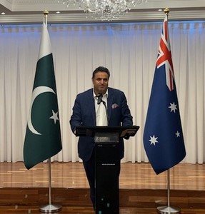 A person standing at a podium with flags behind him
Description automatically generated