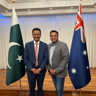 Two men standing in front of flags
Description automatically generated