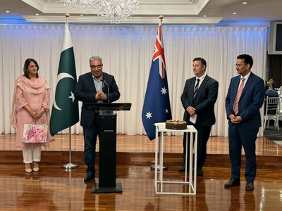 A group of people standing in front of flags
Description automatically generated