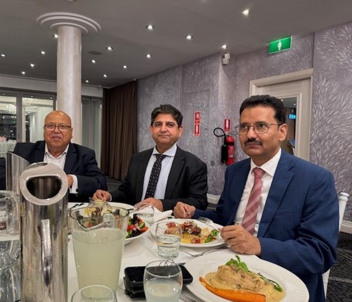 A group of men sitting at a table with food
Description automatically generated