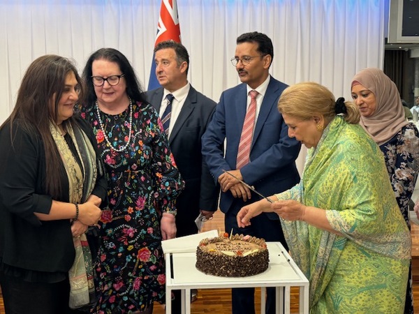 A group of people standing around a cake
Description automatically generated