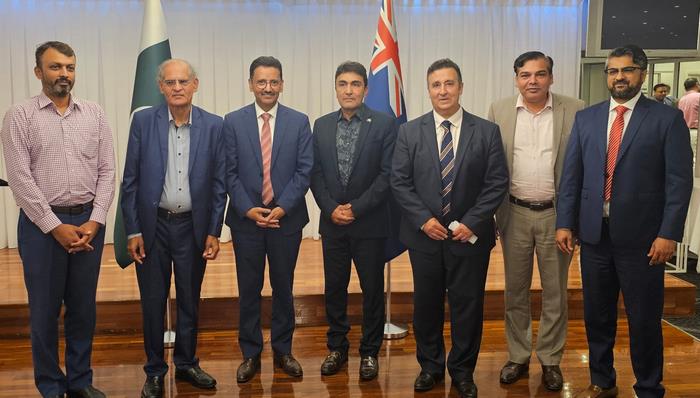 A group of men standing in front of flags
Description automatically generated