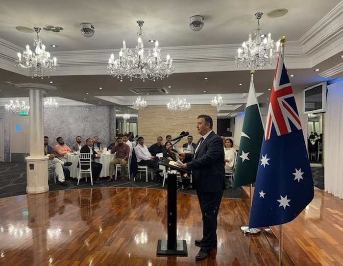 A person standing at a podium with flags in front of him
Description automatically generated