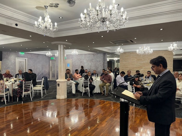 A person standing at a podium with a microphone in front of a group of people
Description automatically generated
