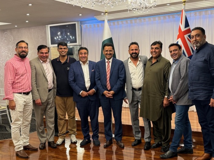 A group of men standing in a room with flags
Description automatically generated