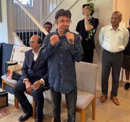 A person holding a microphone in front of a group of men
Description automatically generated
