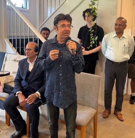 A person holding a microphone in front of a group of men
Description automatically generated