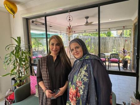 Two women standing in front of a glass door
Description automatically generated