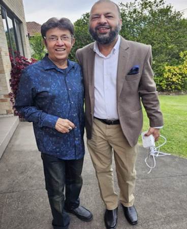 Two men standing together smiling
Description automatically generated