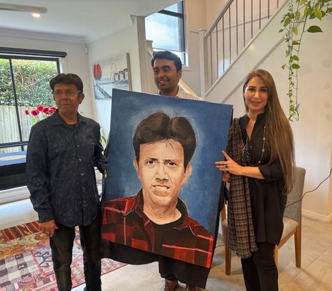 A group of people holding a painting
Description automatically generated