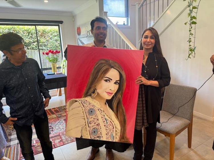 A group of people holding a painting
Description automatically generated
