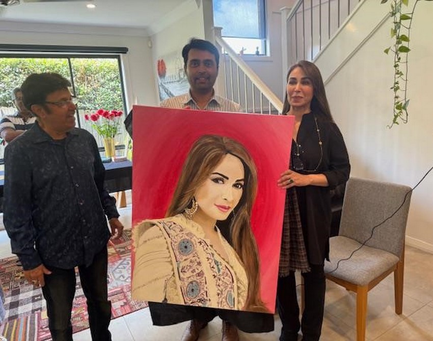 A group of people holding a painting
Description automatically generated