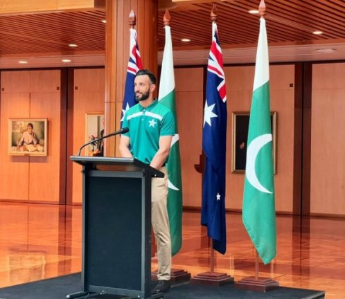A person standing at a podium with flags behind him
Description automatically generated