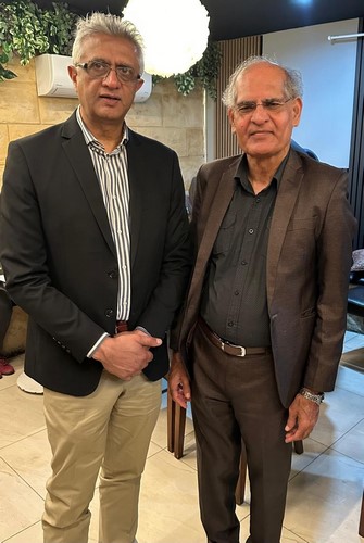 Two men standing together in a room
Description automatically generated