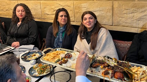 A group of people sitting at a table with food on it
Description automatically generated