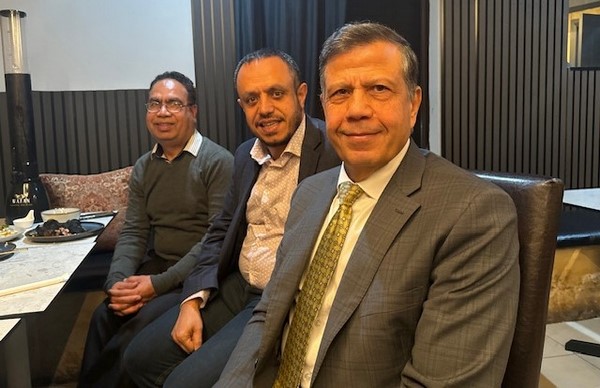 A group of men sitting in a room
Description automatically generated