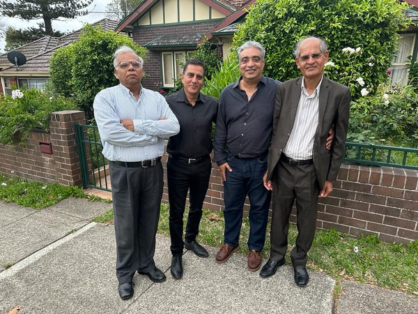 A group of men standing in front of a brick wall

Description automatically generated