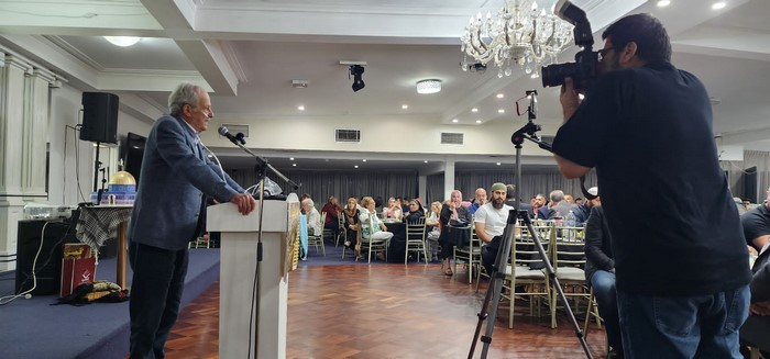 A person standing at a podium with a microphone

Description automatically generated