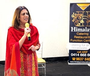 A person in a red dress holding a microphone
Description automatically generated