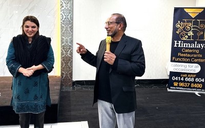 A person holding a microphone and pointing at another person
Description automatically generated