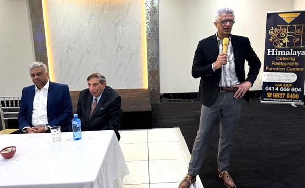 A person speaking to a group of men
Description automatically generated