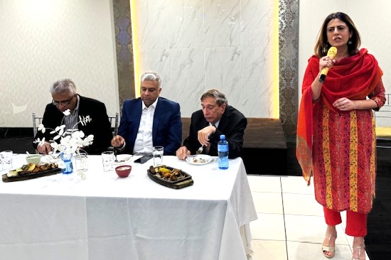 A person standing next to a table with people around it
Description automatically generated