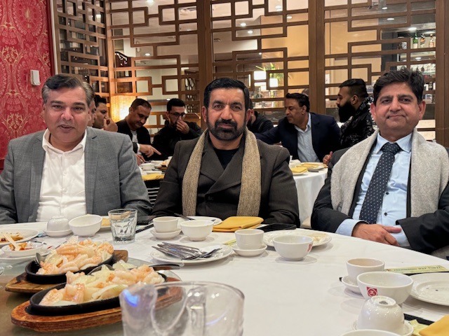 A group of men sitting at a table with food
Description automatically generated