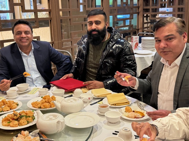 A group of men sitting at a table with food
Description automatically generated